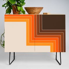 an orange, brown and white sideboard with a potted plant sitting on top