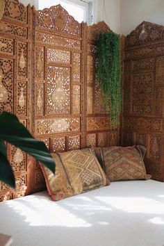 a bed sitting under a window next to a wooden wall with carved wood panels on it