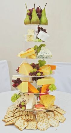 a tower of cheeses, crackers and pears on a table