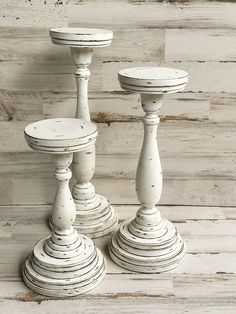 two white wooden candlesticks sitting next to each other on top of a wood floor