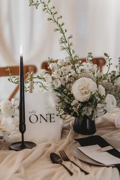 the table is set with white flowers and black candlesticks for an elegant centerpiece