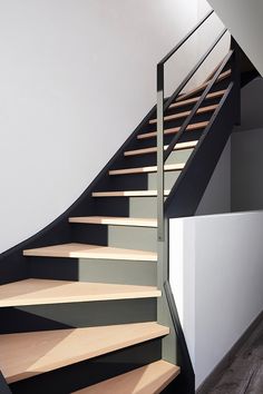 a set of stairs with wooden treads and black handrail in an empty room