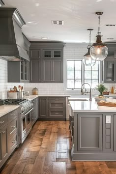 a large kitchen with gray cabinets and wood flooring, along with an island in the middle