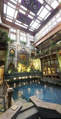 an indoor swimming pool in the middle of a building with lots of plants growing on it