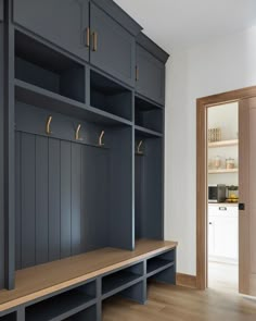 an empty room with blue cabinets and wooden benches in the center, next to a door