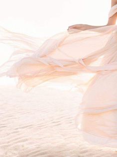 a woman in a white dress walking on the beach