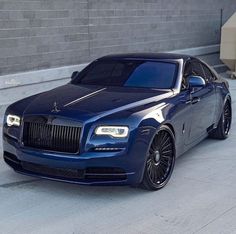 a blue rolls royce parked in front of a building