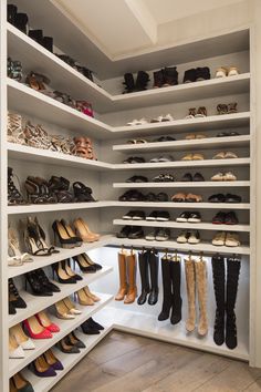 a walk in closet filled with lots of shoes and high heeled boots on shelves