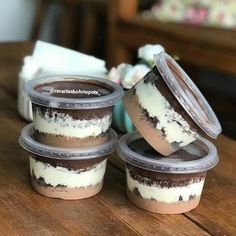 four plastic containers filled with desserts sitting on top of a wooden table