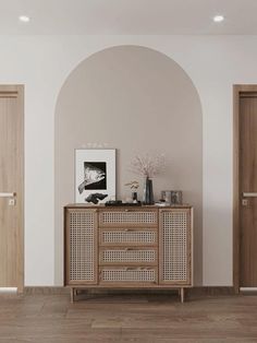 an empty room with two doors and a sideboard in the center, next to a vase on top of a wooden cabinet