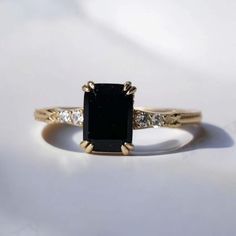 a black and white diamond ring sitting on top of a white surface with gold accents