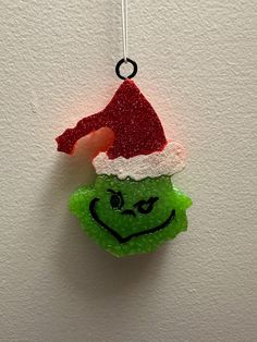 a green christmas ornament with a red santa hat