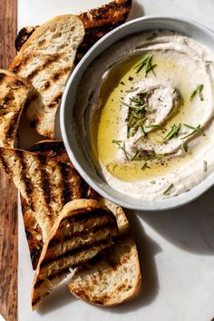 a bowl of hummus and grilled bread on a plate