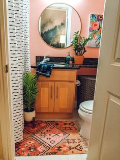 a bathroom with a sink, toilet and mirror in it's corner next to a potted plant