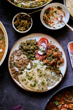 a table topped with plates filled with different types of food next to bowls of rice and vegetables