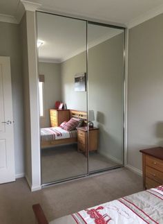 a bedroom with a bed, dresser and mirror on the wall in front of it