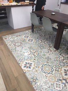 a person standing in front of a table with chairs and a rug on the floor