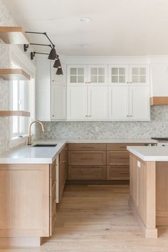 an empty kitchen with white cabinets and wood floors