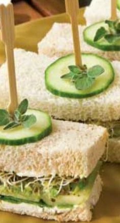 cucumber and cheese sandwiches with toothpicks in them on a yellow plate