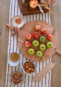 apples, nuts and other foods are arranged on a wooden platter next to candles