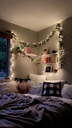 an unmade bed with christmas lights on the headboard