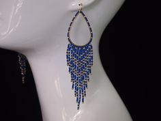 a white mannequin head with blue beaded earrings on it