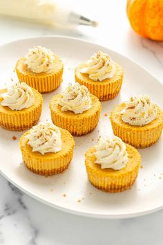 small cupcakes with frosting on a white plate next to an orange peel