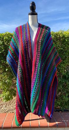 a colorful knitted shawl sitting on top of a mannequin