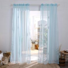 a room with a bed, rug and blue sheer curtains on the windowsills