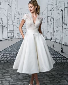 a woman in a white dress standing on a cobblestone street with buildings painted on the wall behind her