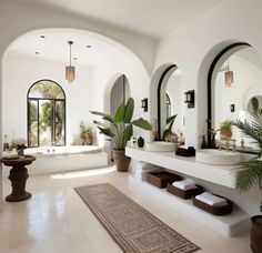 a large bathroom with two sinks, mirrors and potted plants on the counter top