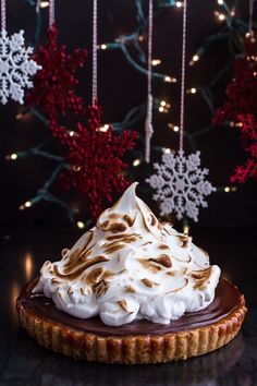 a chocolate tart topped with whipped cream on top of a table next to snowflakes