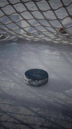 an ice hockey puck sitting on top of snow covered ground next to a goalie net