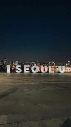 the sign is lit up at night in front of a cityscape with lights