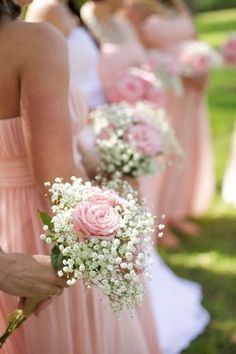 the bridesmaids are holding their bouquets with pink roses and baby's breath