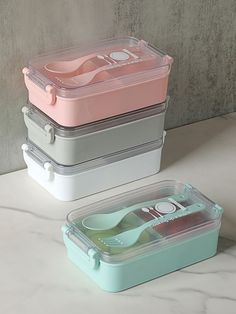 three plastic containers with spoons in them on a white countertop next to each other