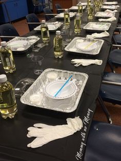 a long table is set up with empty plates and gloves on it for an event