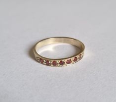 Solid gold Garnet half eternity ring, Garnet stacking ring, stacking gemstone rings, January birthstone ring, Garnet gold ring Solid gold, handmade half eternity stacking ring, stoned with 7 beautiful deep red gemstones.  This multistone ring is beautiful alone or stacked together with other rings and is colorful and pretty on your finger.  The ring is available in 9k or 14k solid gold- yellow, white or rose. It is also available in nickel free, 14 karat gold plating over brass or silver and in solid sterling silver.  A perfect engagement ring or just a beautiful gift for you.  Dimensions: The ring width is about 2 mm. Multiple ring sizes are available. if you need an additional different sizes just convo me. The price is for one ring. For other rings I make: https://www.etsy.com/il-en/sho 14k Gold Eternity Band With Birthstone, 14k Gold Ruby Half Eternity Ring, 14k Gold Ruby Ring With Half Eternity Design, 14k Yellow Gold Eternity Band With Birthstone, Yellow Gold 14k Eternity Band With Birthstone, Stackable Ruby Ring In 14k Gold With Round Band, Yellow Gold Ruby Ring With Stackable Round Band, 14k Gold Half Eternity Birthstone Ring With Round Band, Garnet Gold Ring