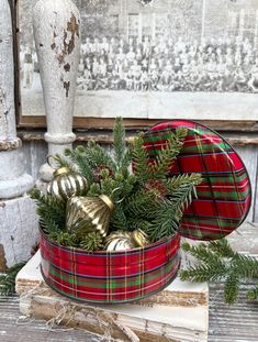 a red plaid christmas bowl filled with ornaments on top of a wooden table next to a vase