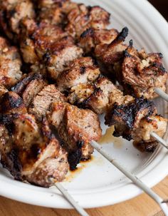 several skewers of meat on a white plate