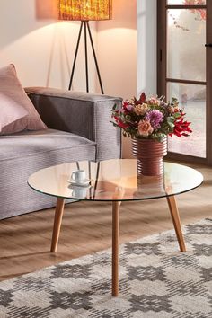 a living room scene with focus on the coffee table and flowers in front of the couch