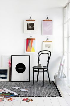 a chair sitting on top of a rug next to a wall with pictures hanging above it