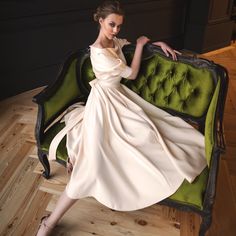 a woman in a white dress sitting on a green couch