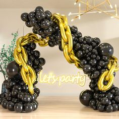 black and gold balloons are arranged in the shape of an o - shaped letter on a table