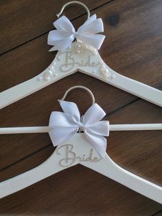 two white wooden clothes hangers with bows and the word b is for bride on them