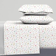 three pillows are stacked on top of each other next to two sheets and one pillow