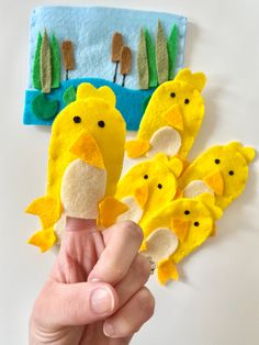 a hand holding a finger puppet with yellow birds on it