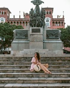 a woman sitting on steps in front of a statue