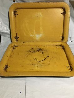 an old yellow metal box sitting on top of a white sheeted tablecloth covered floor