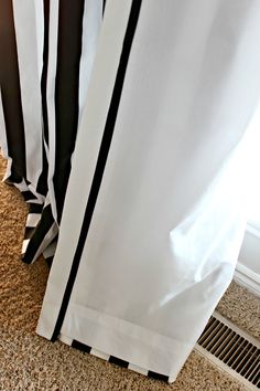 black and white curtains are hanging in front of a heat grate on the floor